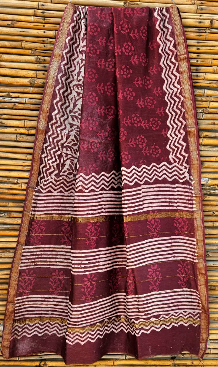 maroon and white hand-block printed Maheshwari or Chanderi silk/cotton blend saree with traditional motifs and a golden zari border.