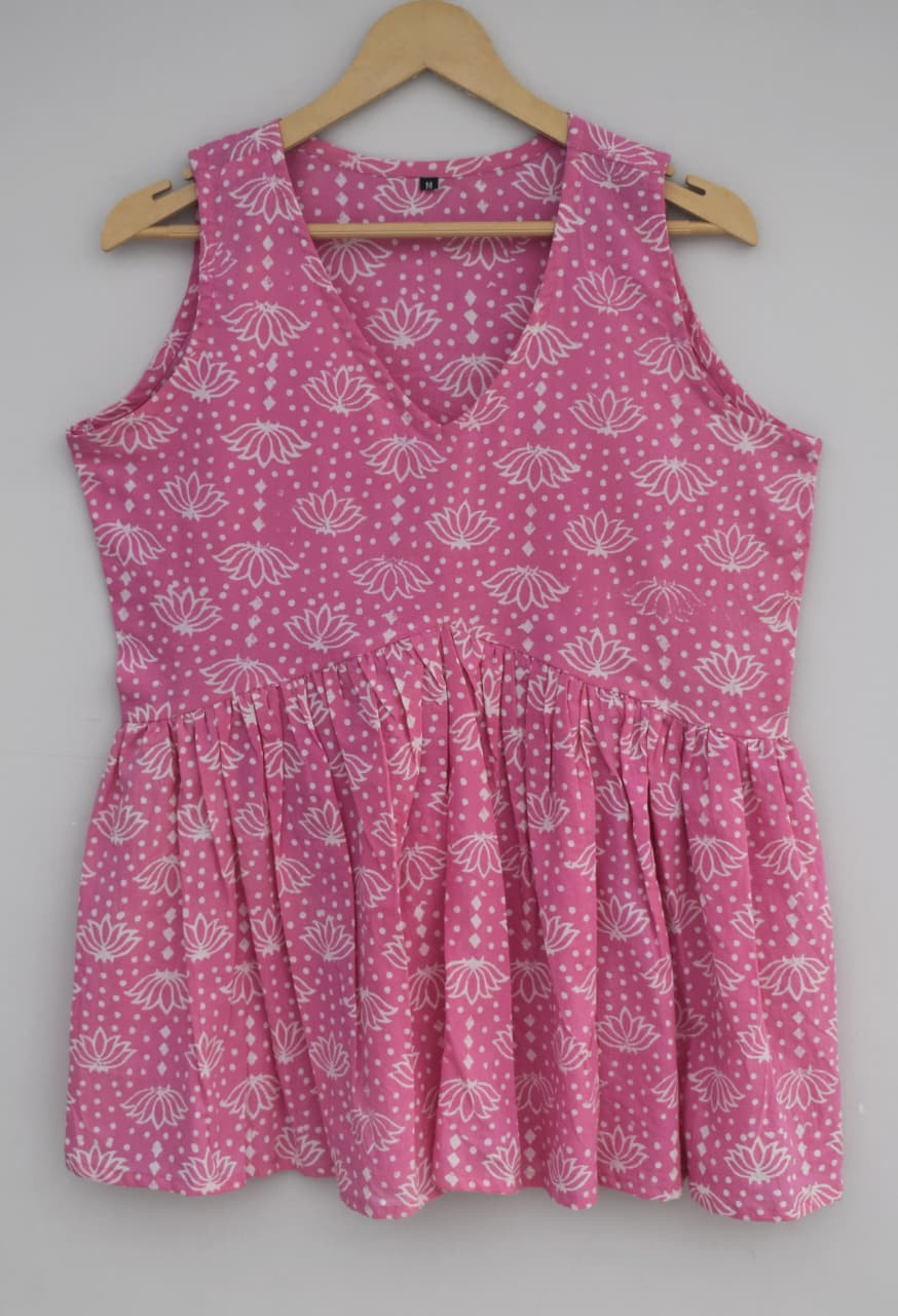 a pink, hand-block printed, cotton, sleeveless peplum top with a white lotus and dot pattern.