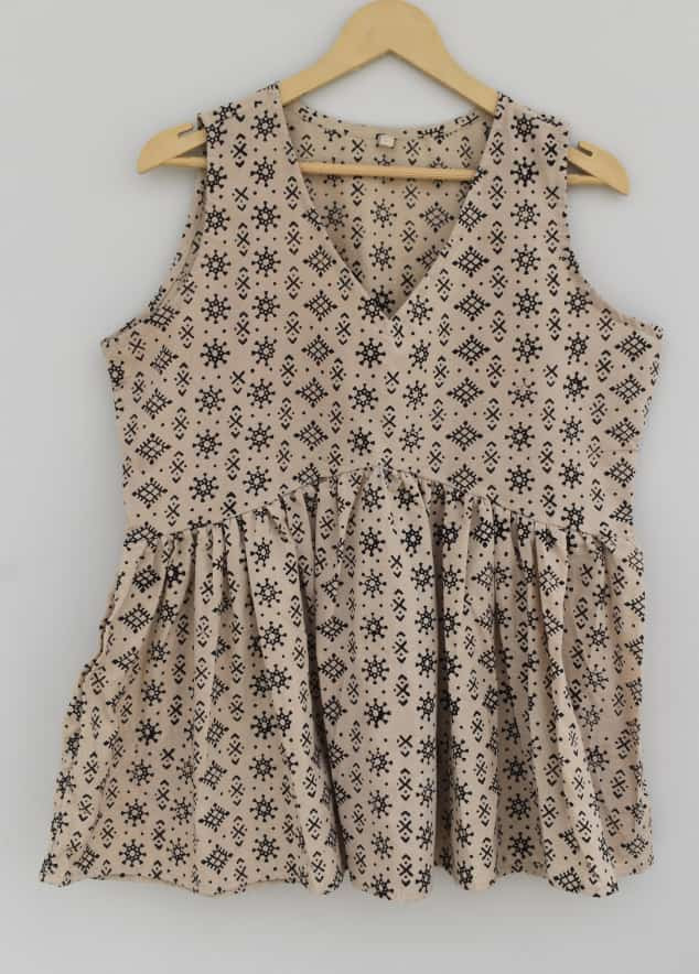 A beige or cream-colored, hand-block printed, cotton, sleeveless top with a black geometric pattern.